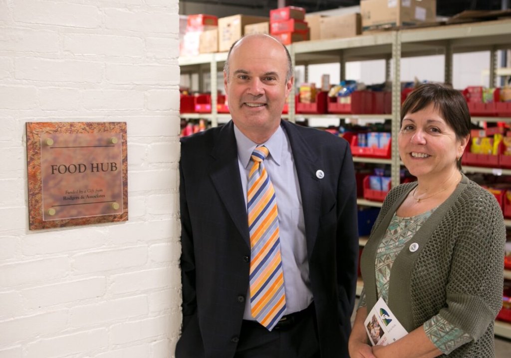 Rick and Jessica standing next to their plaque at the Food Hub